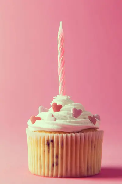 ピンクの背景に隔離されたクリーム スパイク 誕生日のろうそくが付いている1つのきれいな装飾されたマフィン — ストック写真