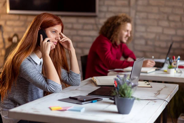 Modern bir ofiste çalışan iş arkadaşları; modern bir iş yerinde çalışan bir kadın telefon görüşmesi yapıyor.