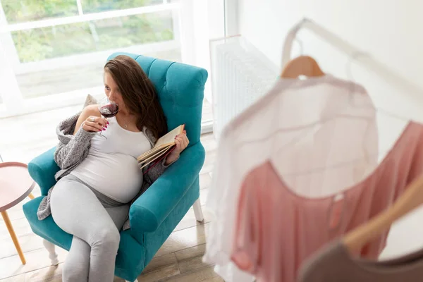 Gyönyörű Terhes Egy Karosszékben Ablaknál Könyvet Olvas Szederbort Iszik — Stock Fotó