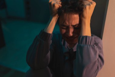 Yüzü makyajla kaplanmış, elleri ve ağlayarak yerde oturan çaresiz bir kadın.