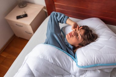 Yüksek açılı bir manzara. Pijama giymiş güzel bir kadın. Sabahları yatakta uzanıyor.