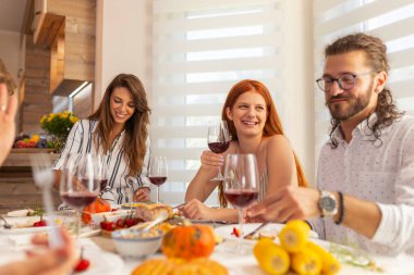 Bir grup genç arkadaş masanın etrafında toplanmış, evde akşam yemeği veriyorlar.