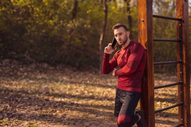 Aktif genç adam egzersiz yaparken telefonda konuşuyor.