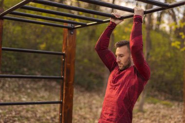 Spor kıyafetleri içinde erkekler barfiks çekerken bir sokak idman parkında spor yapıyorlar.