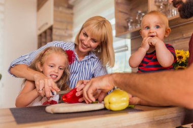 Güzel, mutlu bir aile öğle yemeği pişirirken, anne ve kız sebze keserken baba ve oğul evde vakit geçirip eğlenirken.