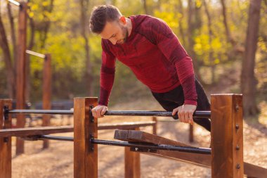 Güneşli bir sonbahar gününde dışarıda spor yapan bir adam, şınav çekiyor.