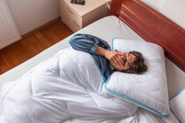 Sabahları pijama giyen, esneyen ve esneyen güzel bir kadının yüksek açılı görüntüsü.