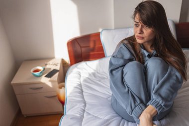 Zihinsel sorunları olan genç bir kadın yalnız ve endişeli, yatakta ağlıyor; stres, endişe ve depresyon kavramı