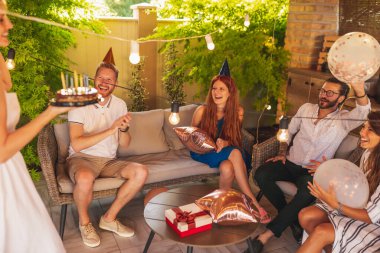 Bir grup arkadaş doğum günü partisinde eğleniyor, doğum günü kızı pasta getirirken şarkı söylüyorlar.