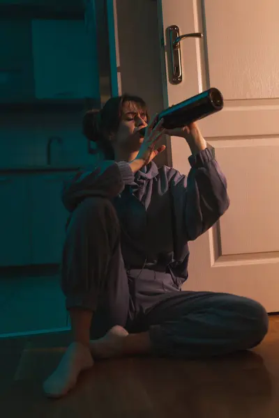 酔っ払った女性が暗闇の床に座ってメイクを塗りつぶし 瓶からワインを飲んで泣いた — ストック写真