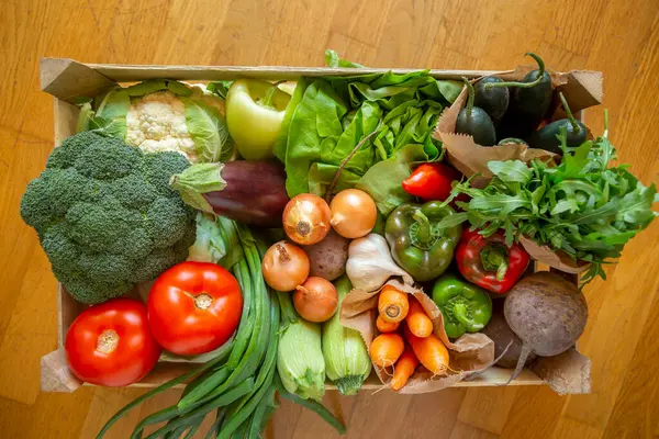 自宅に届いたばかりの新鮮な有機野菜の多種多様な木枠のトップビュー — ストック写真