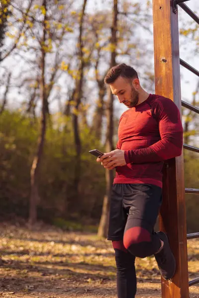 Actieve Jongeman Met Behulp Van Een Smartphone Tijdens Een Workout — Stockfoto
