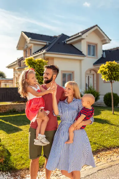 stock image Parents and children having fun standing in front of their new house 