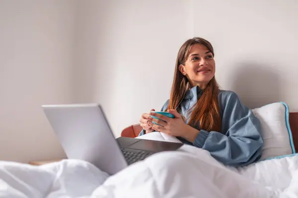 Sabahları Yatakta Oturan Kahve Içen Dizüstü Bilgisayar Kullanan Bir Kadın — Stok fotoğraf