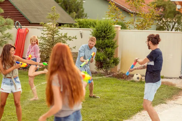 一群年轻的朋友在户外度过夏天的一天 玩水枪 在彼此身上泼水 跑来跑去 互相追逐 玩得很开心 — 图库照片