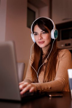 Ev ofisindeki masasında oturan bir kadın dizüstü bilgisayar kullanarak gece geç saatlere kadar çalışıyor, kadın web geliştirici de evden uzakta çalışıyor.