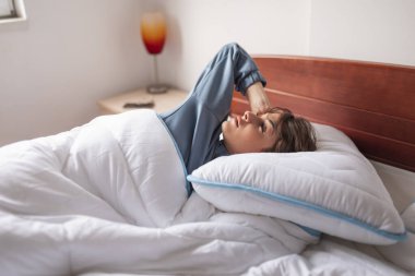 Sabahları pijama giymiş, esneyen ve esneyen güzel bir genç kadın.