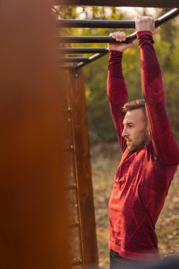 Spor kıyafetleri içinde erkekler barfiks çekerken bir sokak idman parkında spor yapıyorlar.