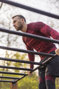 Atletik adam dışarıda spor yapıyor. Spor parkında barfiks çekiyor.