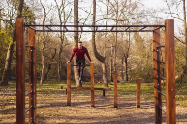 Atletik adam bir sokak idman parkında antrenman yapıyor.
