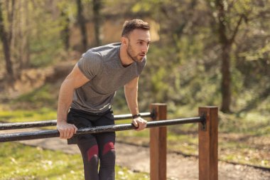 Yakışıklı genç adam bir sokak antrenman parkında antrenman yapıyor.