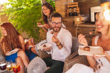 Bir grup genç, arkadaşının doğum gününü kutluyor, pasta yiyor ve eğleniyor.