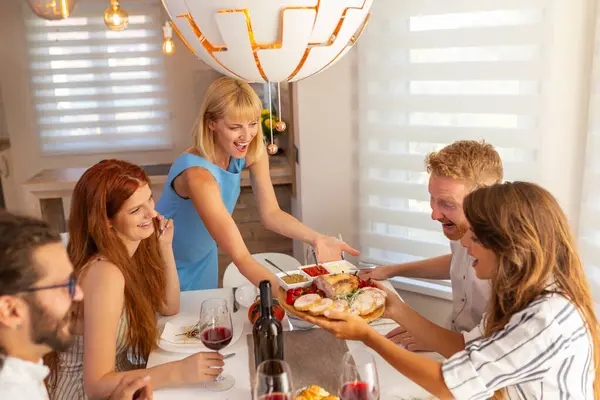 Amigos Divirtiéndose Mientras Cenan Juntos Casa Anfitriona Sirviendo Comida Entreteniendo —  Fotos de Stock