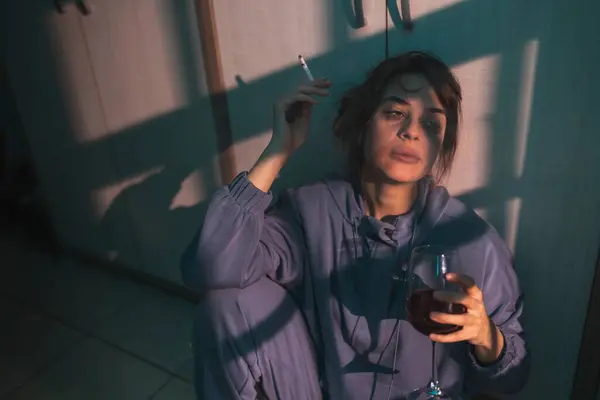 暗闇の床に座り ワインを飲んでタバコを吸い 動揺して絶望する女性 — ストック写真