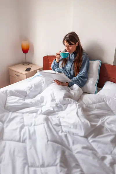 깨어나고 신문을 그녀의 커피를 침대에서 휴식을 취하는 잠옷을 아름다운 — 스톡 사진