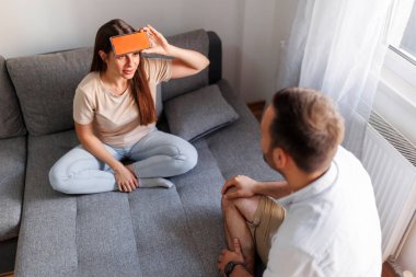 Çift evde sessiz sinema oynayarak eğleniyor, akıllı bir telefon uygulamasından kelimeleri izah ediyor ve tahmin ediyor.