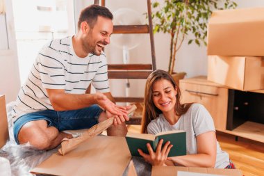 Güzel, genç ve aşık bir çift yeni dairelerine taşınırken karton kutulardan bir şeyler çıkarırken eğleniyorlar.