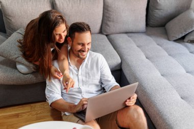 Çift arkadaşlarıyla çevrimiçi sohbet ederken dizüstü bilgisayar kullanıyor ve evde dinleniyor.