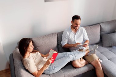 Güzel bir çift sabahları evde birlikte vakit geçirirken kitap okuyor ve kahve içiyor.