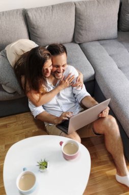 Güzel bir çiftin evdeki dizüstü bilgisayarını kullanarak arkadaşlarıyla görüntülü konuşma yapması.