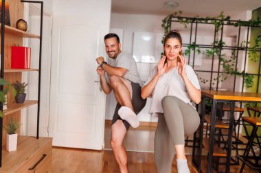 Spor giyim sektöründe aktif genç bir çift evde birlikte çalışıyor, hafif tekmeler atıyorlar.