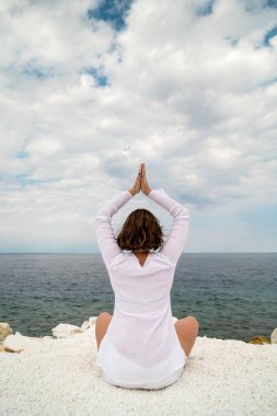 Yunanistan 'ın Thassos adasında, bulutlu bir yaz gününde mermer plajda yoga yapan genç bir kadın.