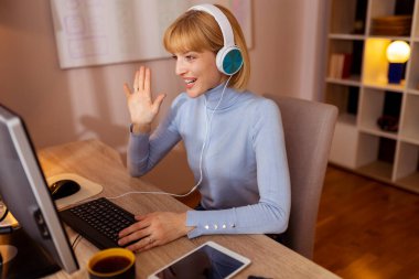 Ofisteki masasında oturan bir kadın, evden uzaktan çalışıyor, konferans sırasında kulaklık takıyor.