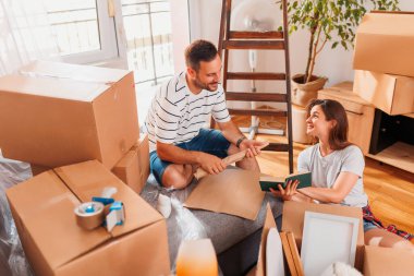 Güzel, genç ve aşık bir çift yeni dairelerine taşınırken karton kutulardan bir şeyler çıkarırken eğleniyorlar.