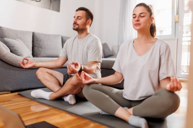 Çift evde meditasyon yaparken dinleniyor.