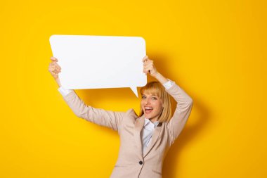 Güzel genç bir kadın, elinde boş bir karton bulut tutuyor. Sarı renkli arka planda, kopyalama alanı ile izole edilmiş.