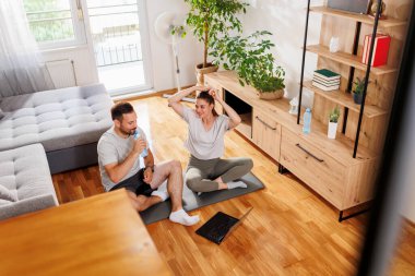 Çift evde online antrenman yaparken mola veriyor, su içiyor ve antrenmana hazırlanıyor.