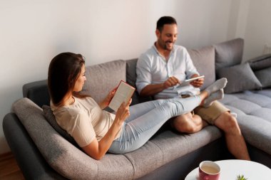 Güzel bir çift sabahları evde birlikte vakit geçirirken kitap okuyor ve kahve içiyor.