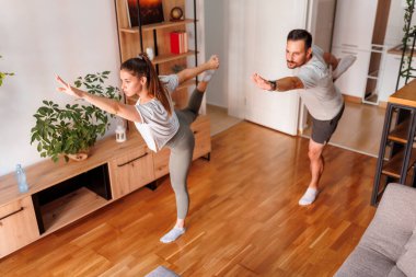 Genç bir çiftin evde birlikte çalışıp yoga yaparak sabah egzersizi yaptıklarını yüksek açılı görmek.