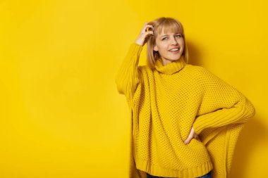 Sarı arka planda gülümseyen genç ve güzel sarışın kadının portresi.