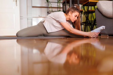 Spor kıyafetli genç bir kadının ev ödevinden sonra yoga minderinin üzerine uzanması.