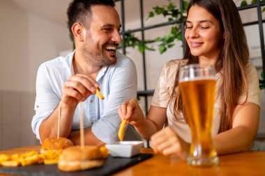 Güzel, genç ve aşık bir çift evde birlikte vakit geçirip, hamburger yiyip, bira içerek eğleniyor.