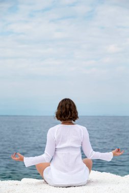 Yunanistan 'ın Thassos adasında, bulutlu bir yaz gününde mermer plajda yoga yapan genç bir kadın.