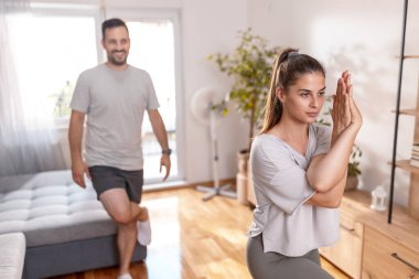 Genç çift evde birlikte çalışıyor, sabah yoga seansı yapıyorlar.