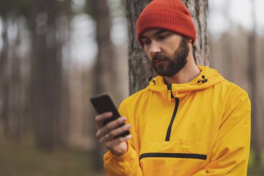 Bulutlu bir sonbahar gününde sabah koşusuna ara verip akıllı bir telefonla internette sohbet eden bir adam.