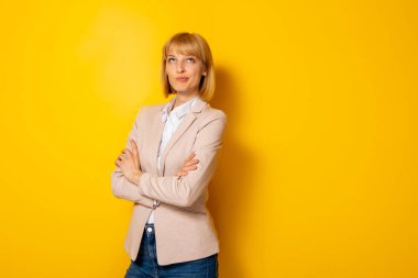 Kendine güvenen iş kadını, kopya alanı olan sarı renkli arka planda izole edilmiş olduğunu düşünüyor.